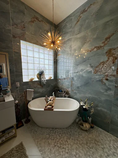 Luxury bathroom remodeling project in Boca Raton by GPS Remodeling featuring marble walls, freestanding tub, and elegant chandelier